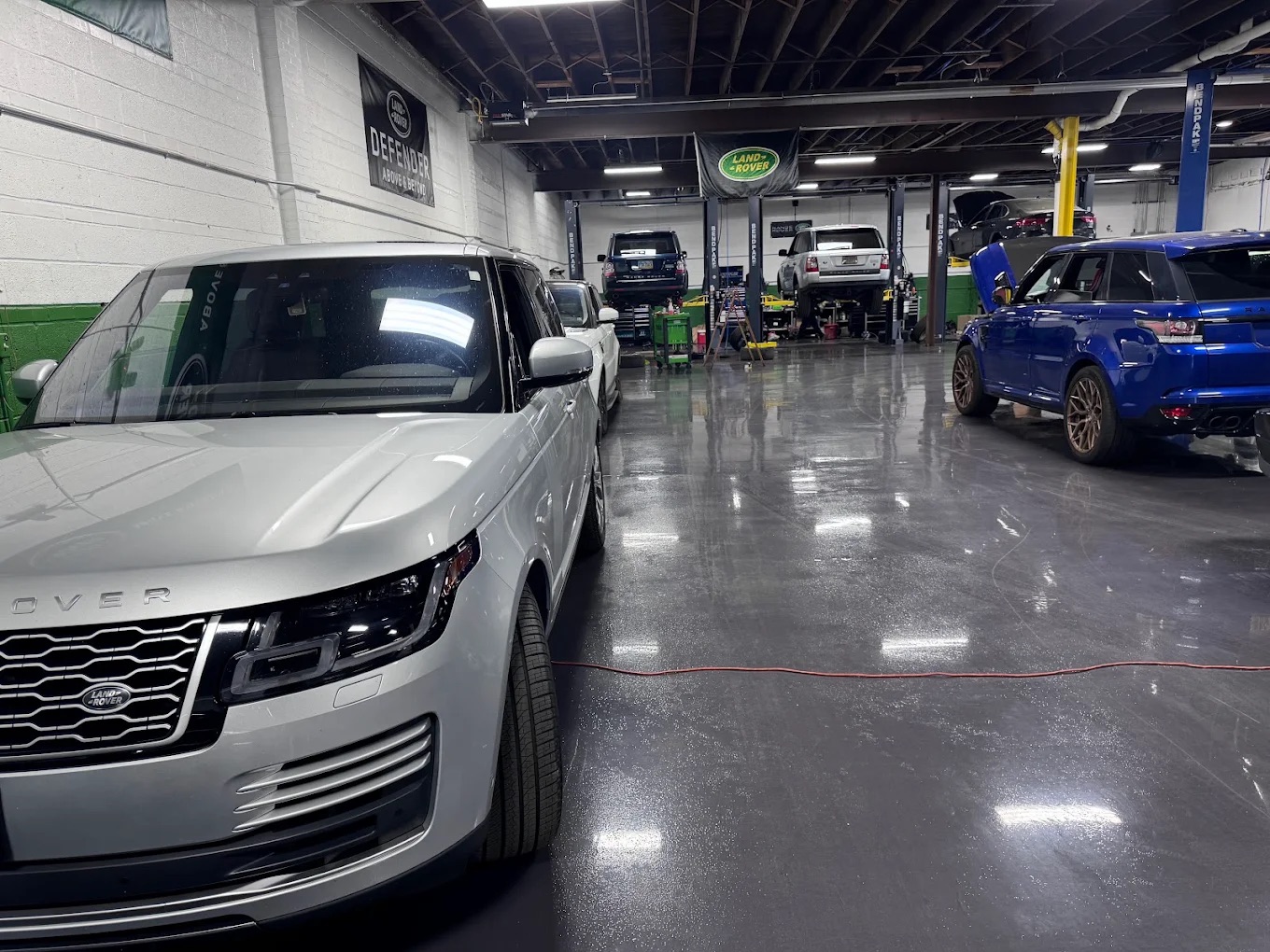 Silver Range Rover parked in the shop aisle with more Rovers on lifts behind