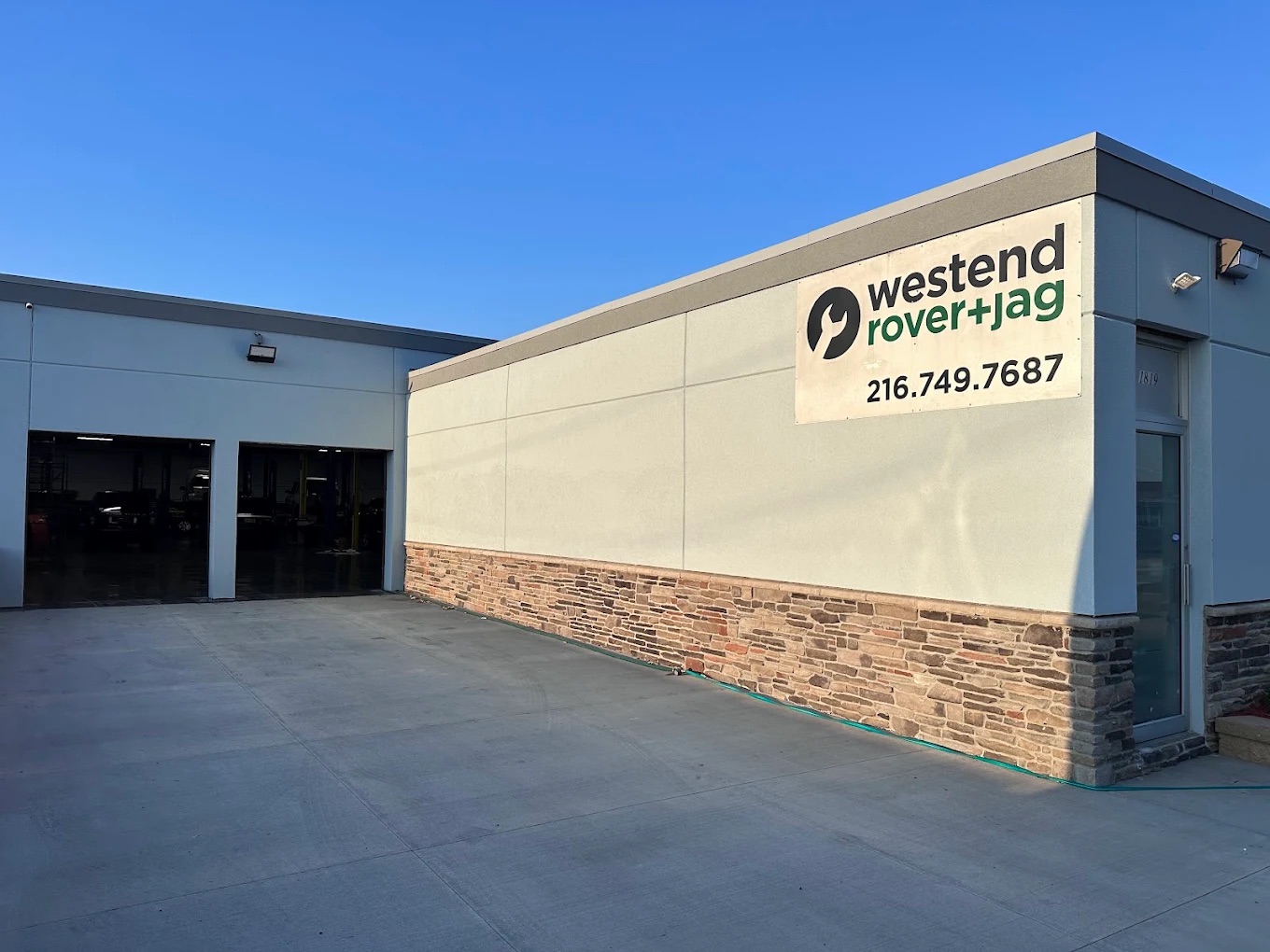 Exterior of Westend Rover + Jag in Cleveland, Ohio, with the shop sign and open service bays