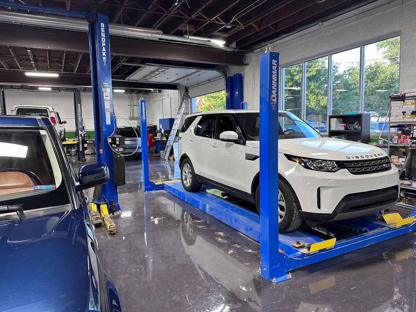 A white Land Rover Discovery raised on a four-post lift in the Westend service bay