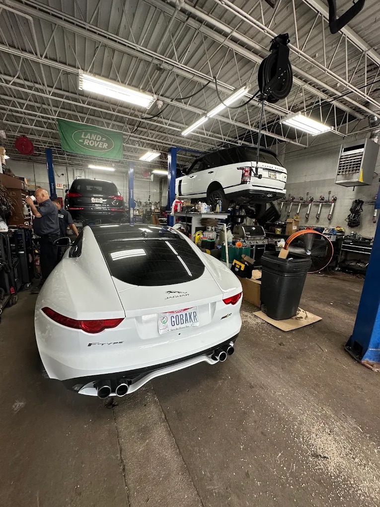A white Jaguar in the bay beside a Range Rover on a lift