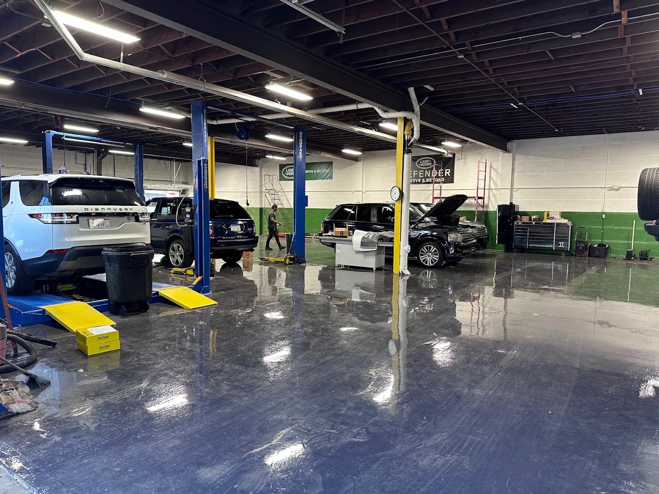Wide view of the Westend service floor with Land Rovers on lifts and a technician at work